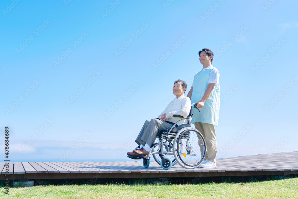 介護士と車椅子に乗る高齢者　屋外