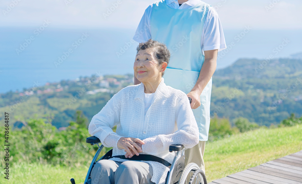 介護士と車椅子に乗る高齢者　屋外