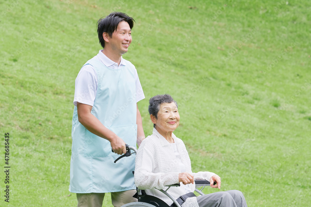 介護士と車椅子に乗る高齢者　屋外