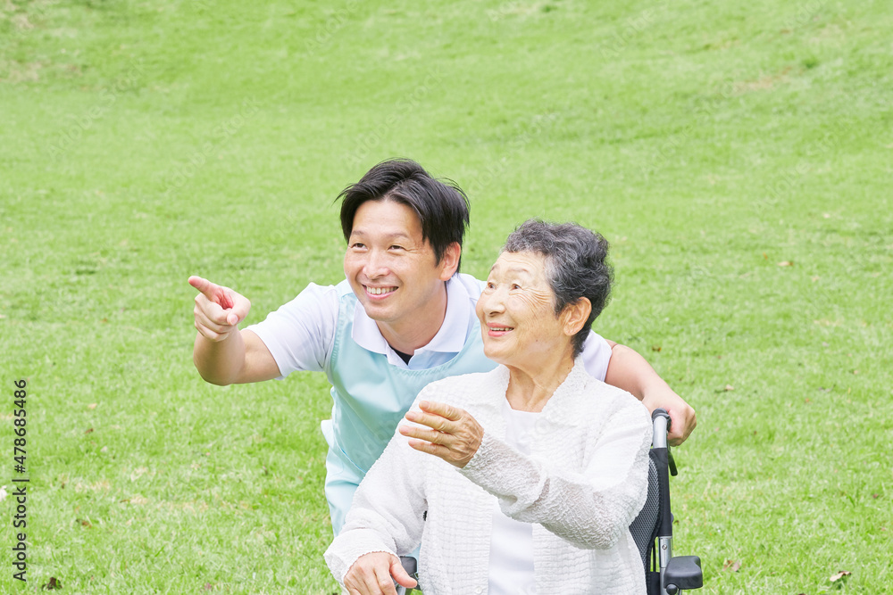 介護士と車椅子に乗る高齢者　屋外