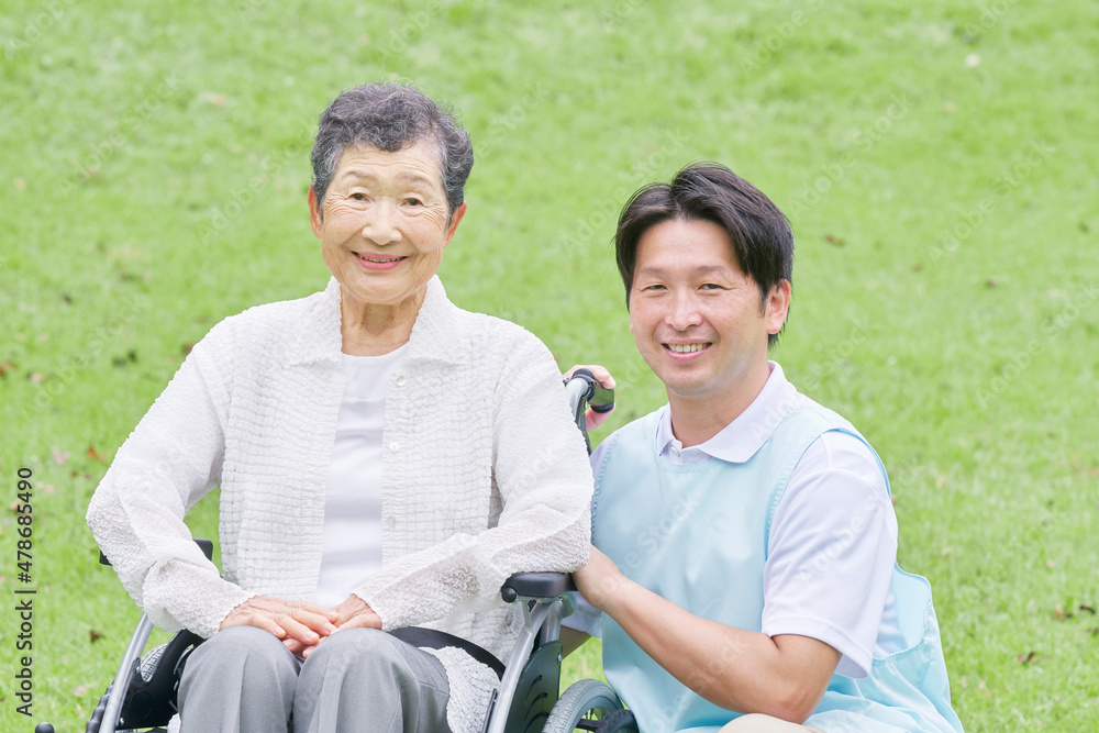 介護士と車椅子に乗る高齢者　屋外