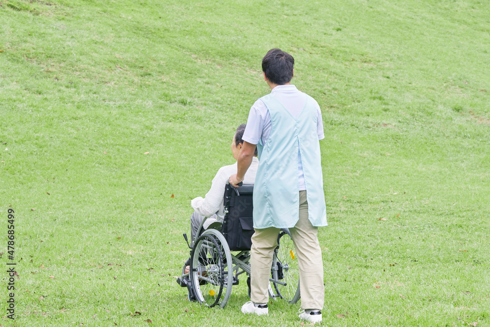 介護士と車椅子に乗る高齢者　屋外