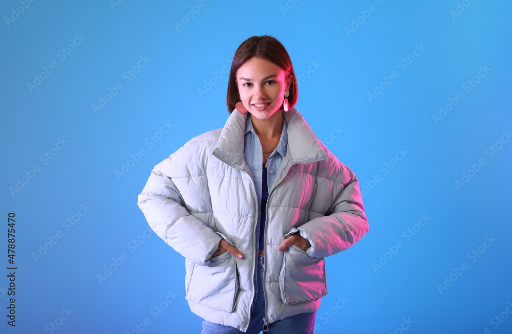 Pretty young woman in stylish warm clothes on color background