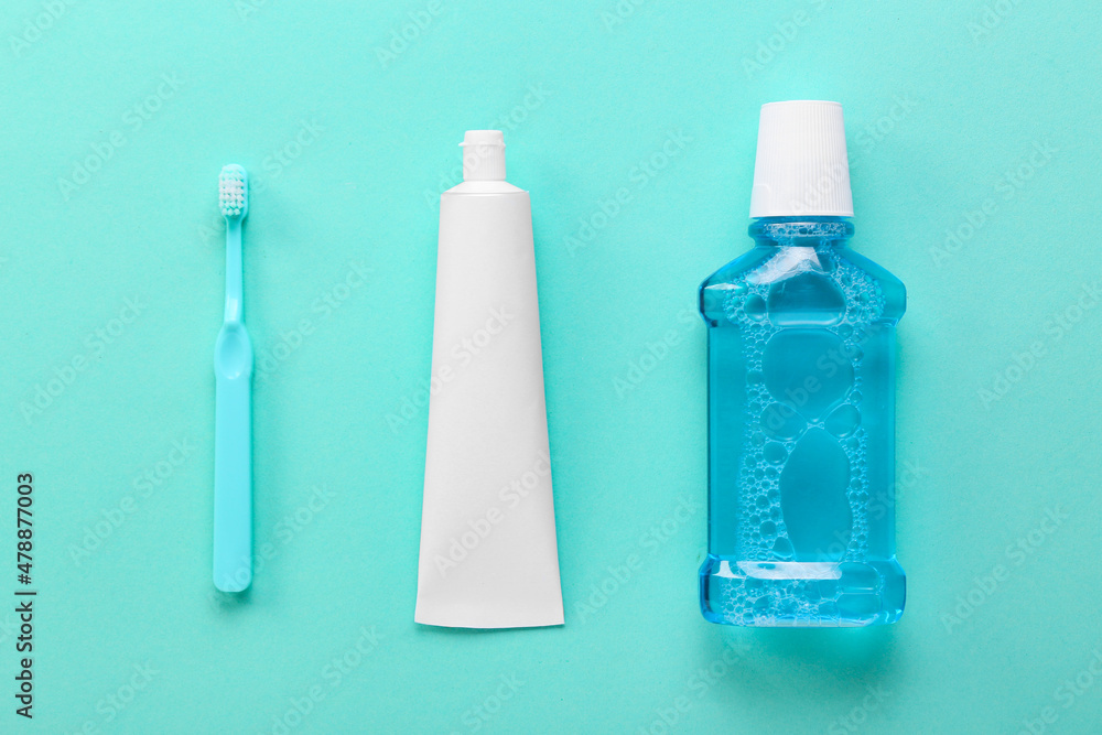 Tube with tooth paste, brush and mouthwash on color background