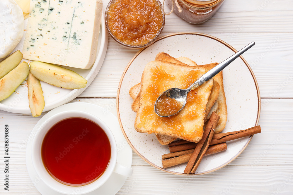 由美味的梨酱、奶酪和一杯茶组成，背景为浅色木质