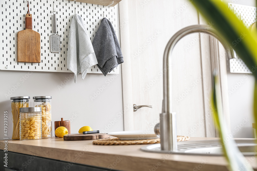 Peg board with kitchenware and napkins hanging on light wall