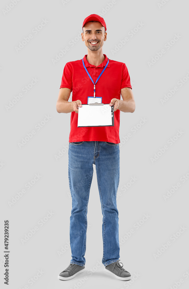 Male courier with clipboard on light background