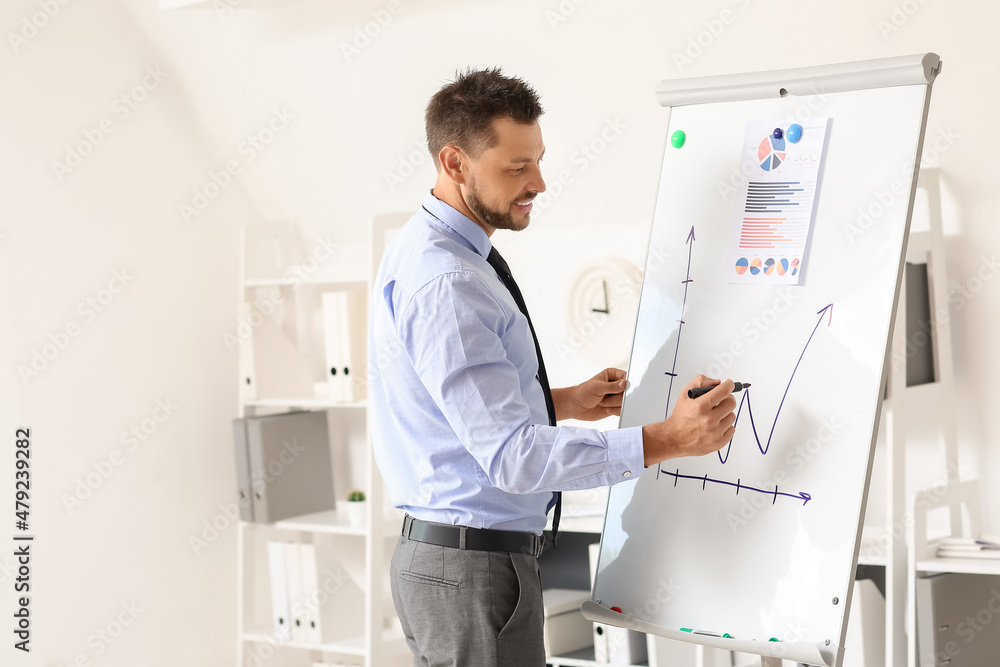 Handsome businessman writing on flipchart in office