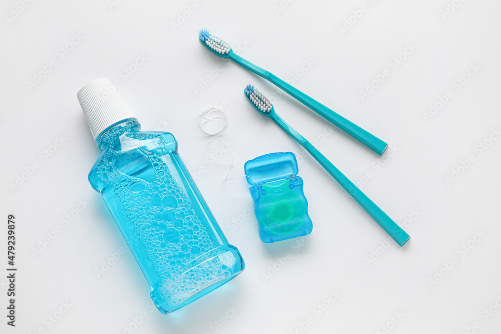 Dental floss with tooth brushes and rinse on white background