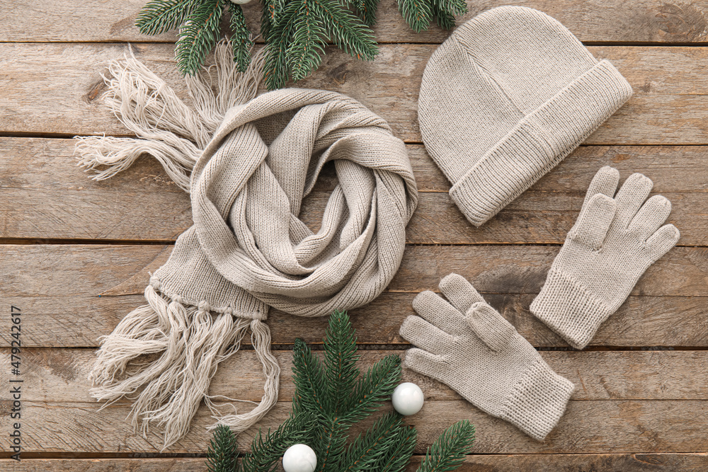 Winter hat, scarf, gloves and Christmas decor on wooden background