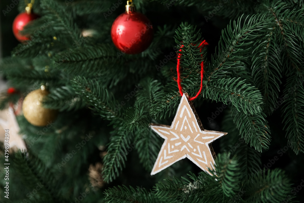 Star made of cardboard hanging on Christmas tree, closeup