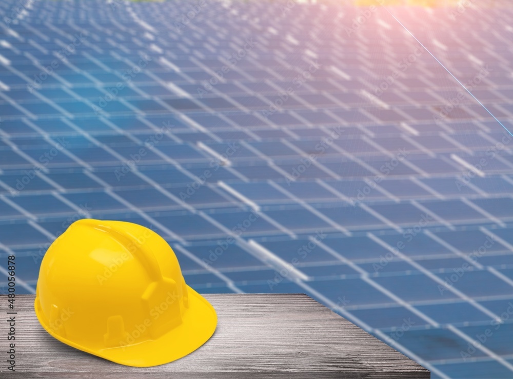 Plastic engineer hard hat placed on the solar panel At a photovoltaic power station