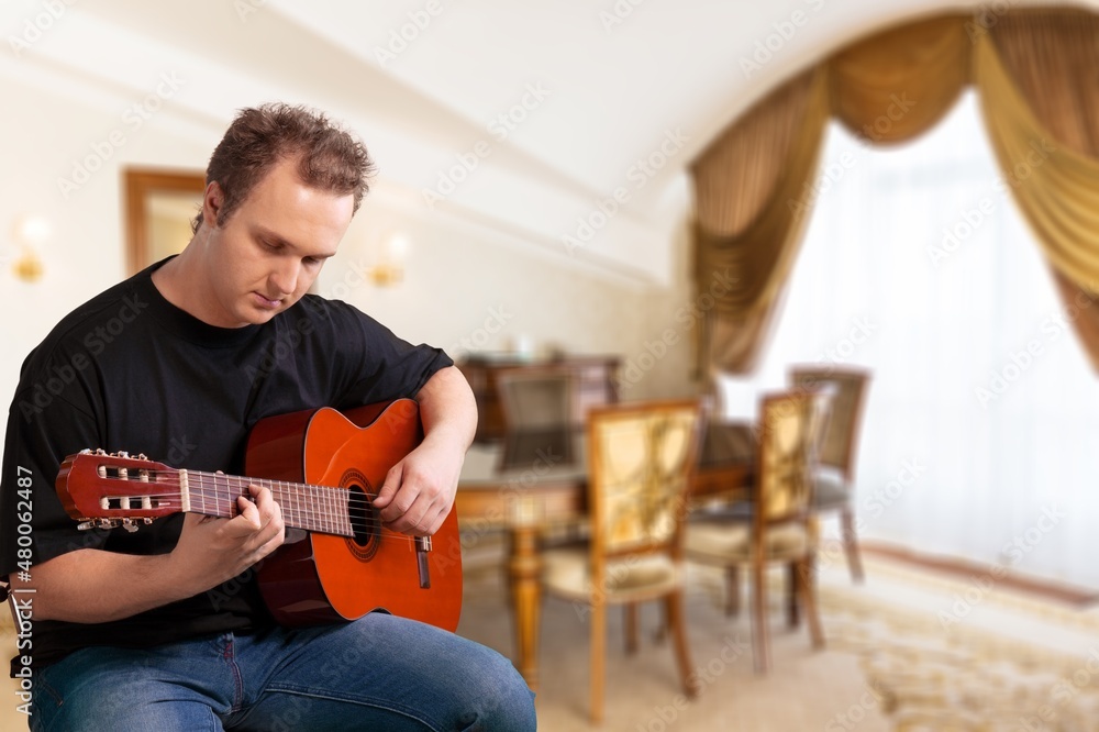 Lifestyle concept. Young musician playing guitar in the living room at home on this weekend.