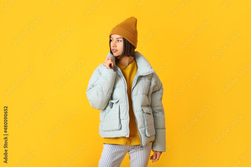 Pretty young woman in stylish warm clothes on color background