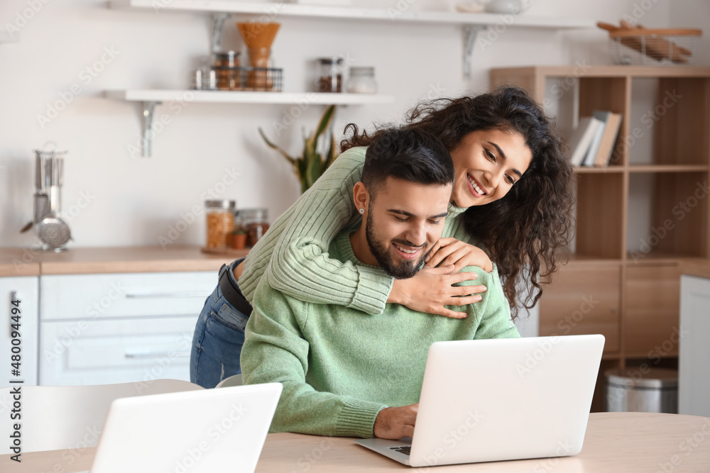 Happy young couple of freelancers with laptops at home