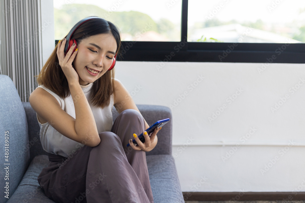 A young woman with a mobile phone listening to music in a comfortable atmosphere in the house.