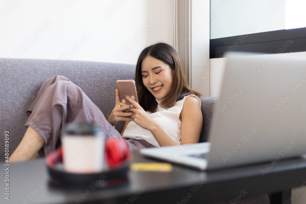 A young woman plays on her mobile phone during her break from online classes at home. Work from home