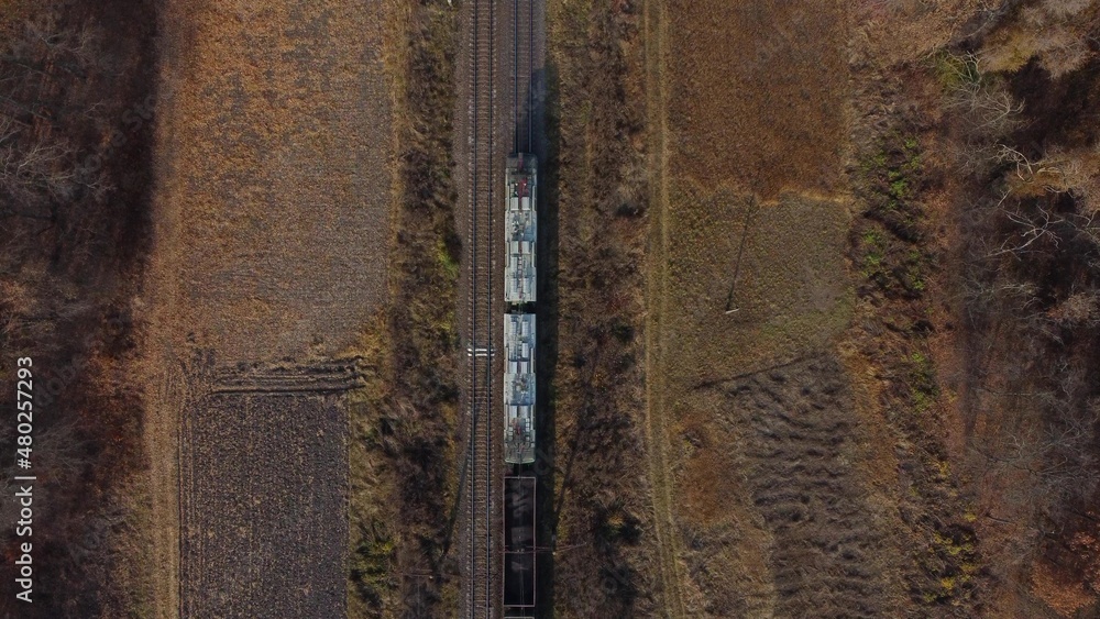 View of train from above. Locomotive pulls railway freight train with wagons filled coal. Aerial Dro