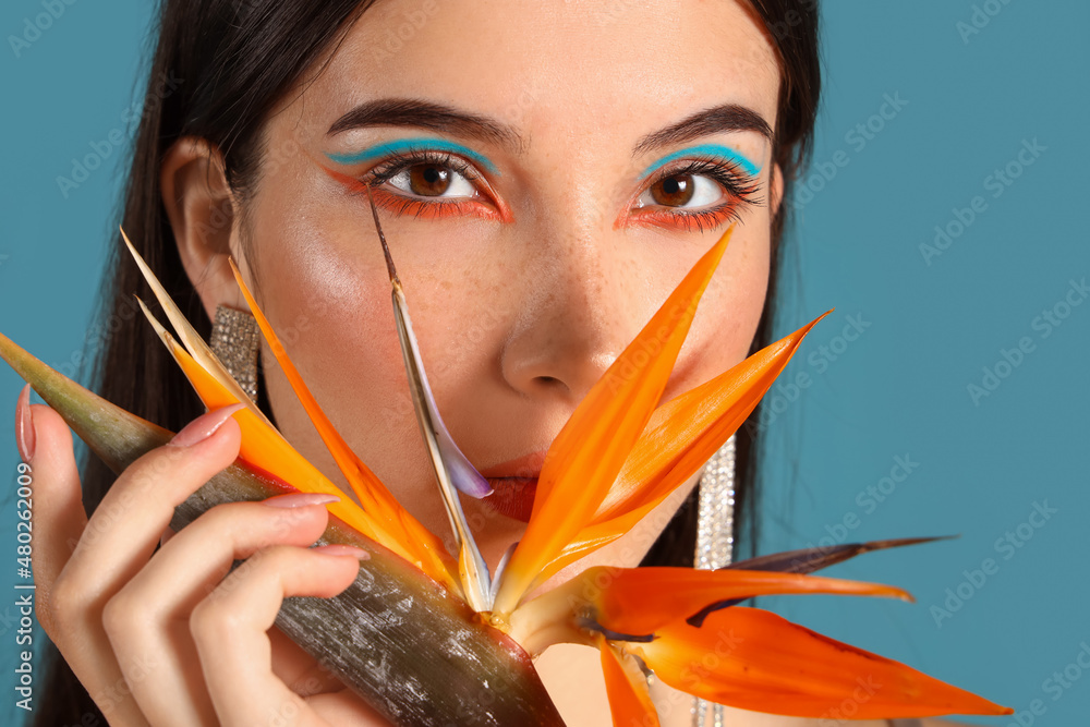 Beautiful young woman with strelitzia flower on color background