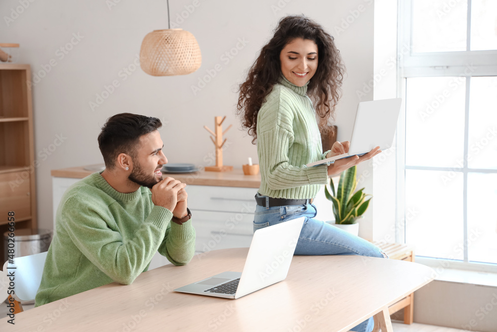 Happy young couple of freelancers with laptops at home