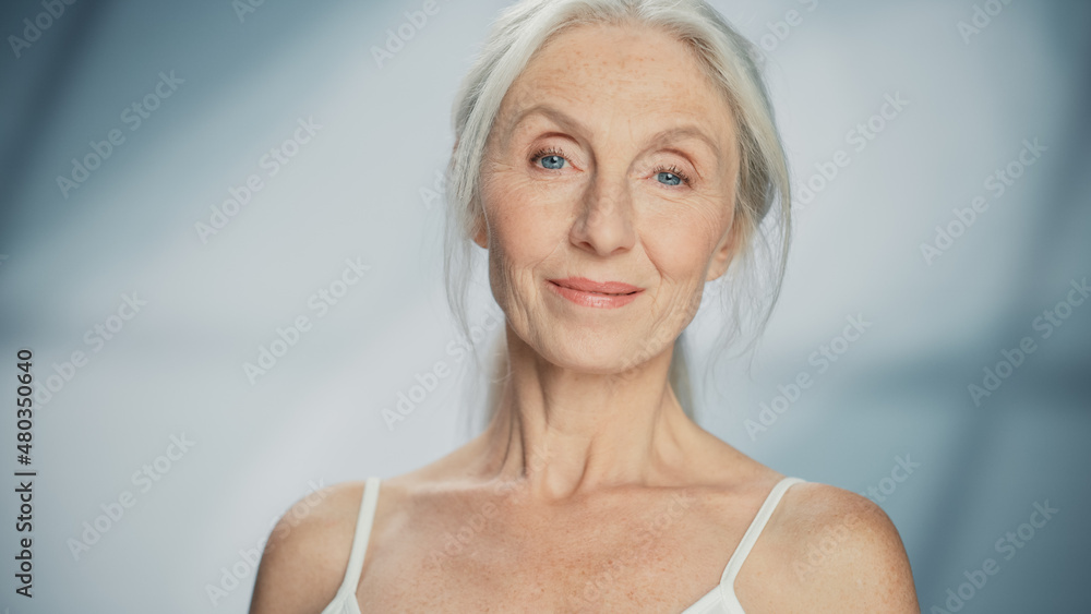 美丽的老年妇女凝视镜头，灿烂微笑的特写肖像。老年美女