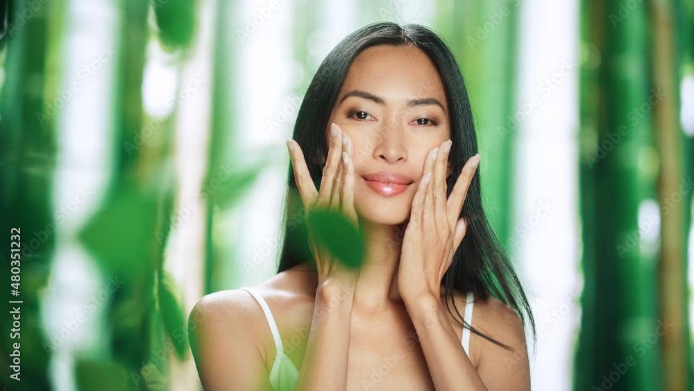 Portrait of Beautiful Asian Woman Gently Applying Face Cream. Young Adult Female Makes Her Skin Soft