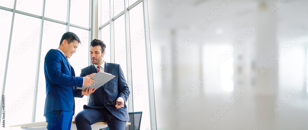 Two business people talk project strategy at office in widen view meeting room. Businessman discuss 