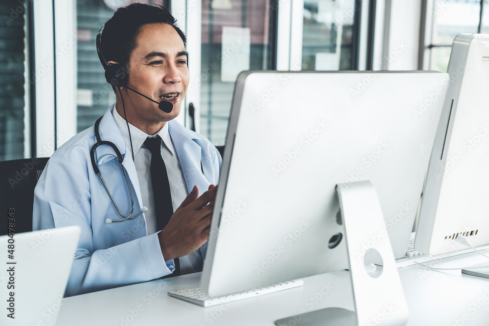 Doctor wearing headset talking actively on video call in a clinic or hospital . Concept of telehealt