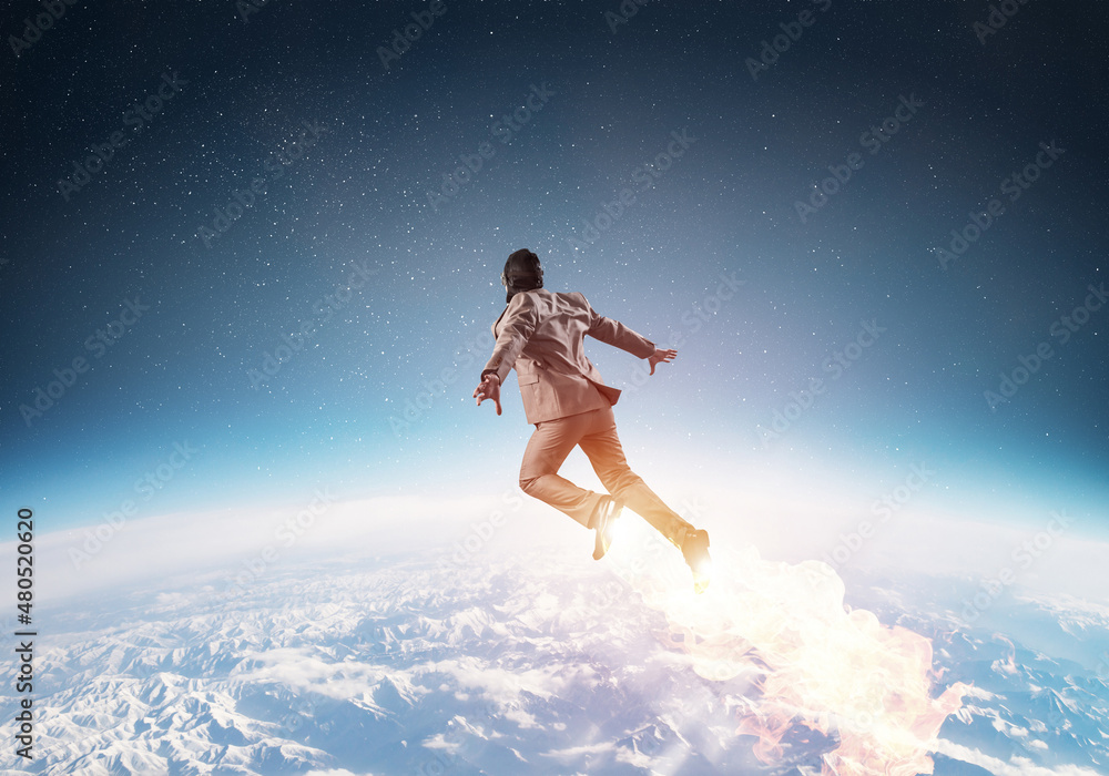 Businessman in suit and aviator hat flying in sky