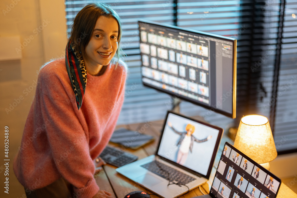 Portrait of a young creative woman work on laptop and desktop computers editing photos at cozy home 