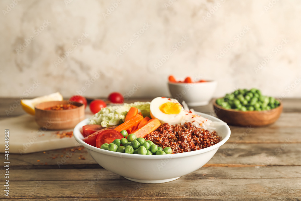 Healthy quinoa bowl with egg on wooden table