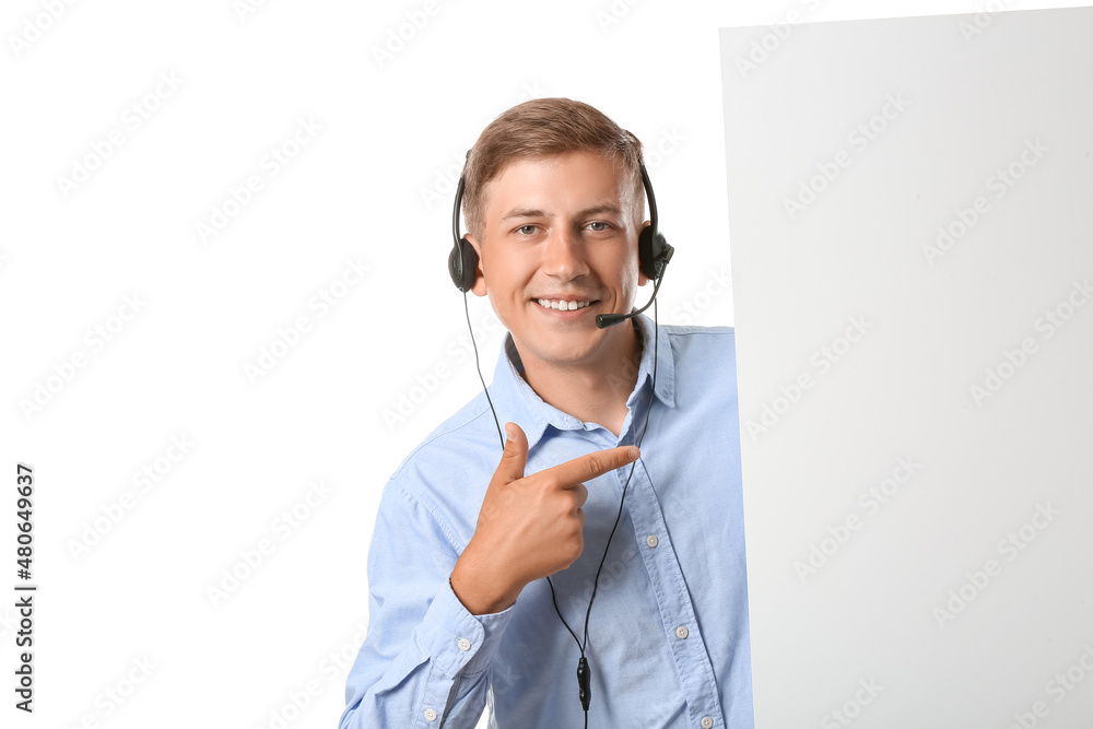 Young consultant of call center in headset pointing at blank paper sheet on white background