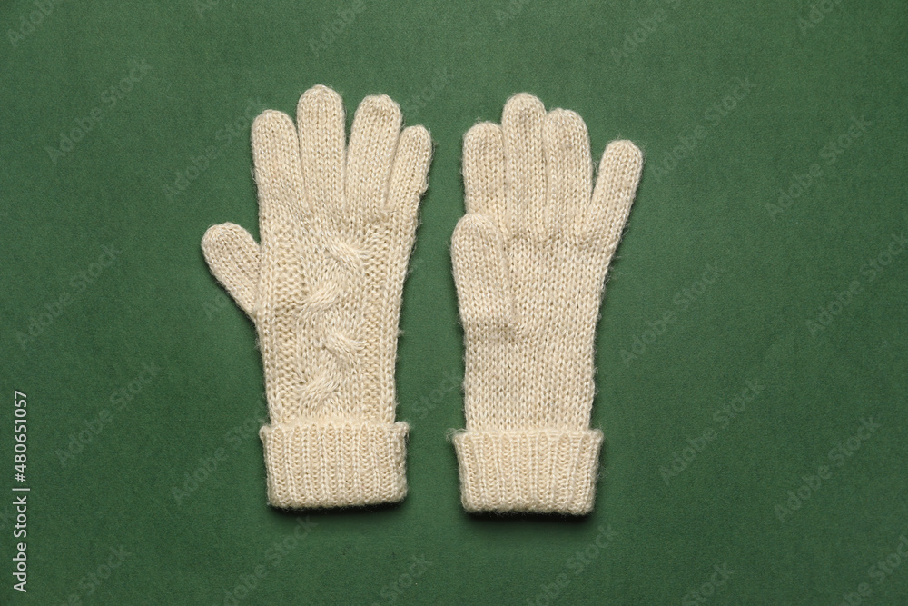 Pair of warm gloves on green background