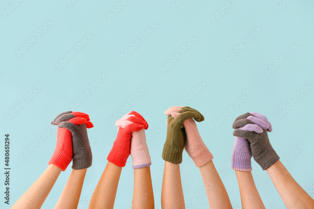 Women in warm gloves holding hands on blue background