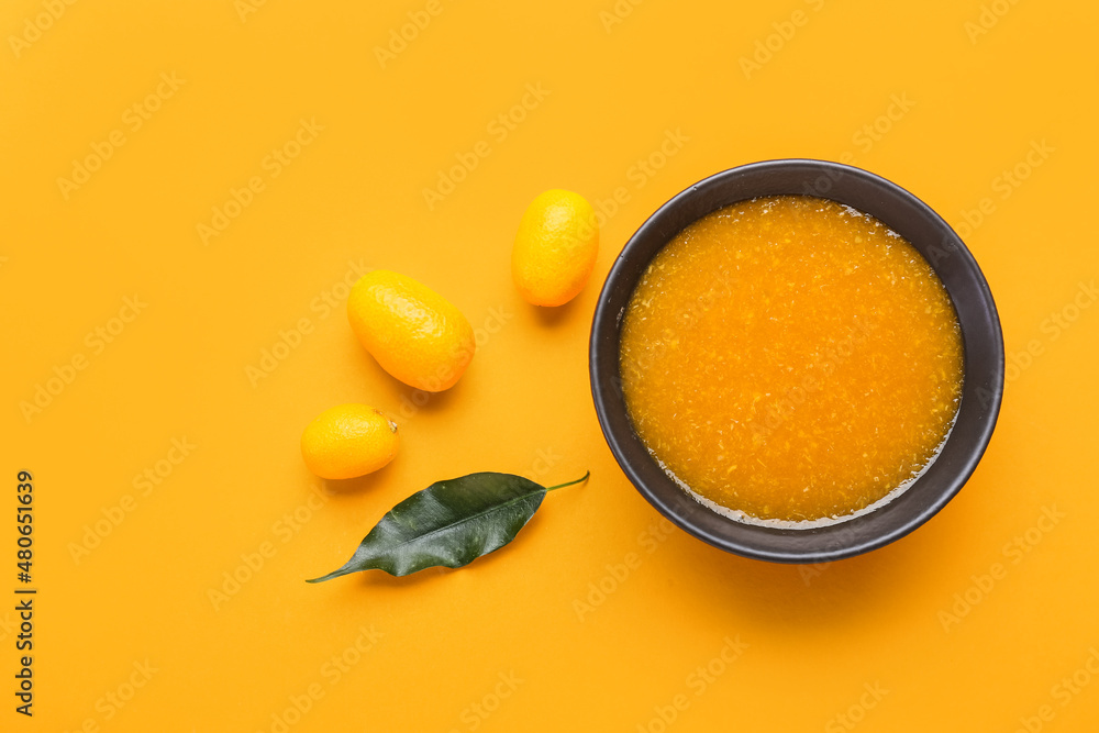 Bowl of tasty kumquat jam and fresh fruits on orange background