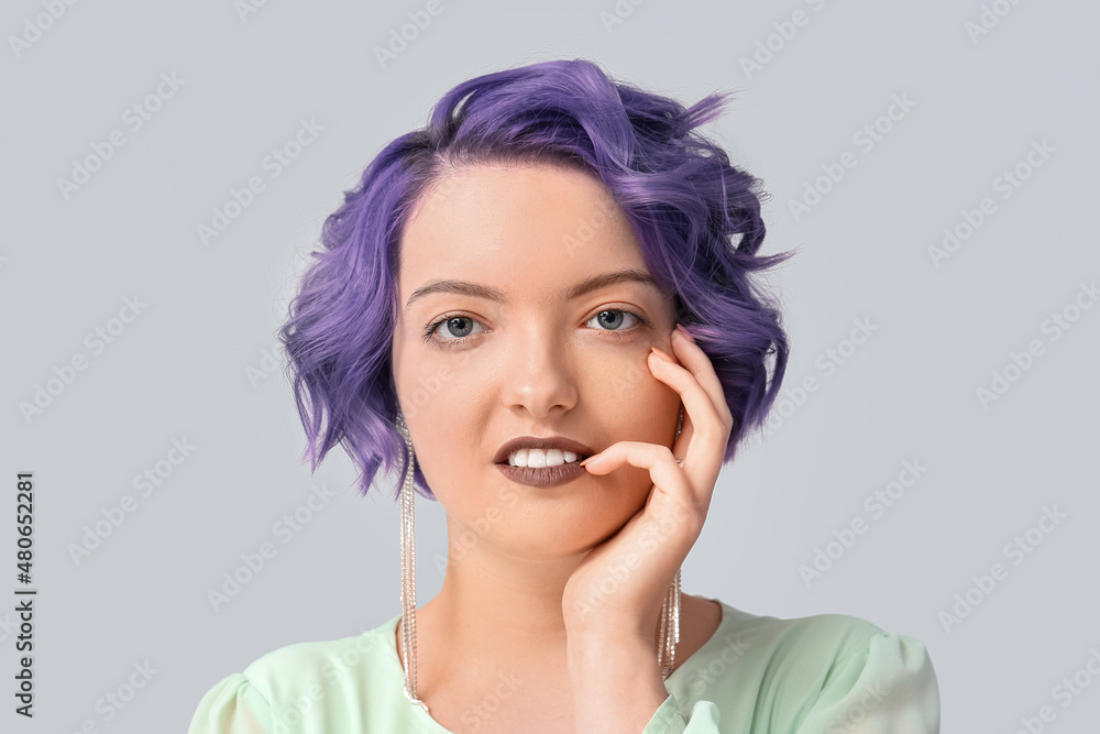 Beautiful young woman with violet hair on light background. Very Peri - color of year 2022