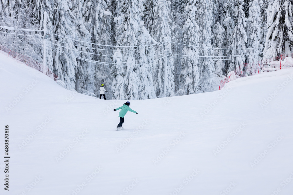 Young girl snowboarder snowboarding down the slope in Finland