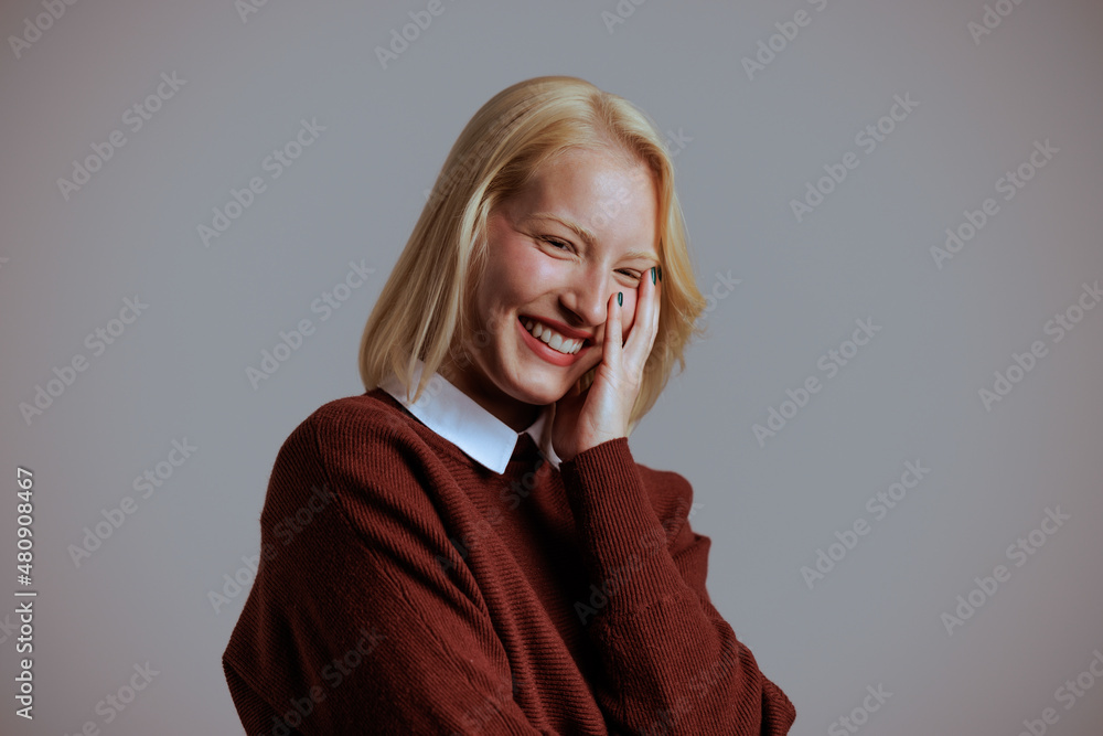 Portrait of blonde smling woman, rejoices in the neutral background.