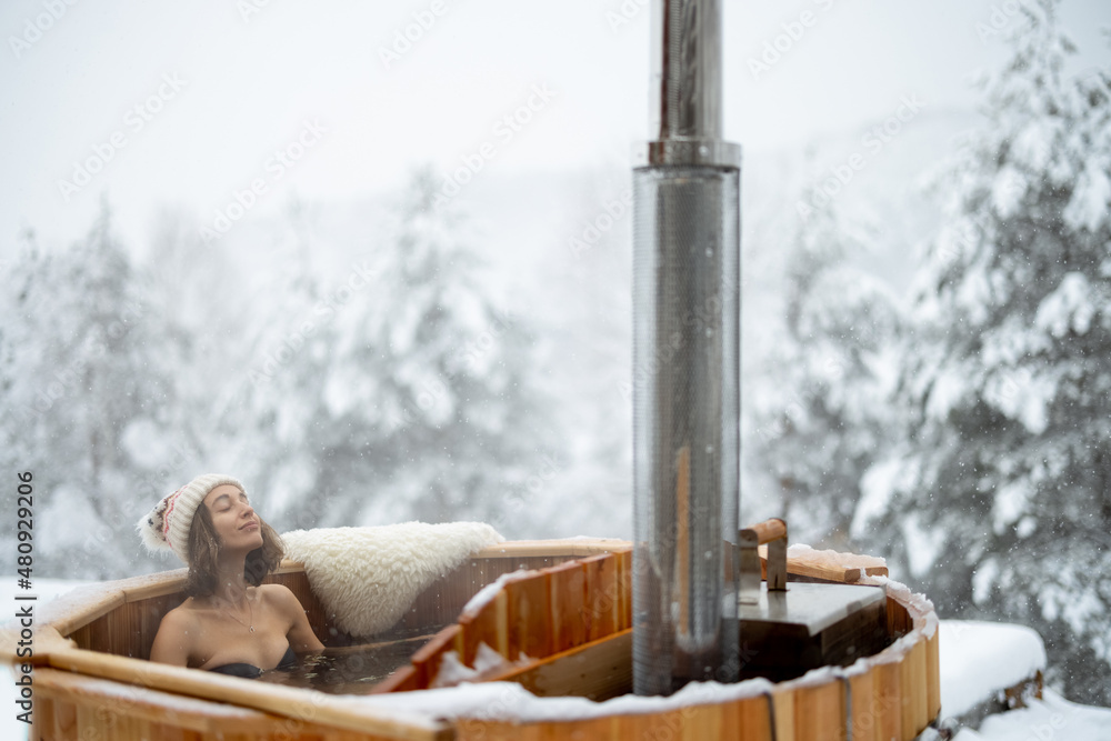 女人在户外洗热水澡放松，在雪山享受温泉。冬季假期在