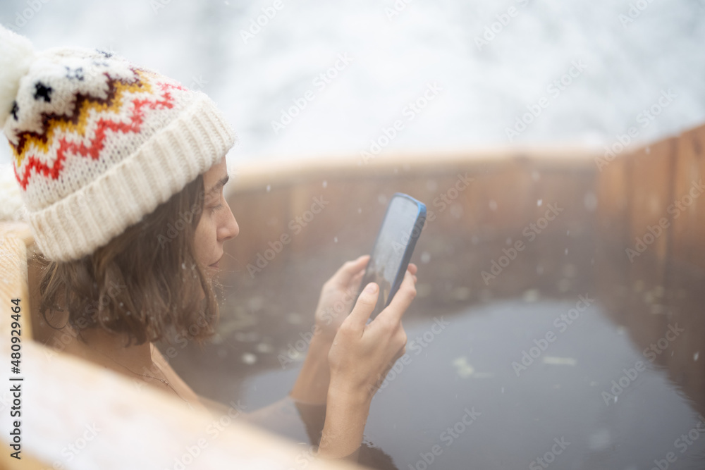 女人在室外洗热水澡，在雪山享受温泉。冬季休闲和