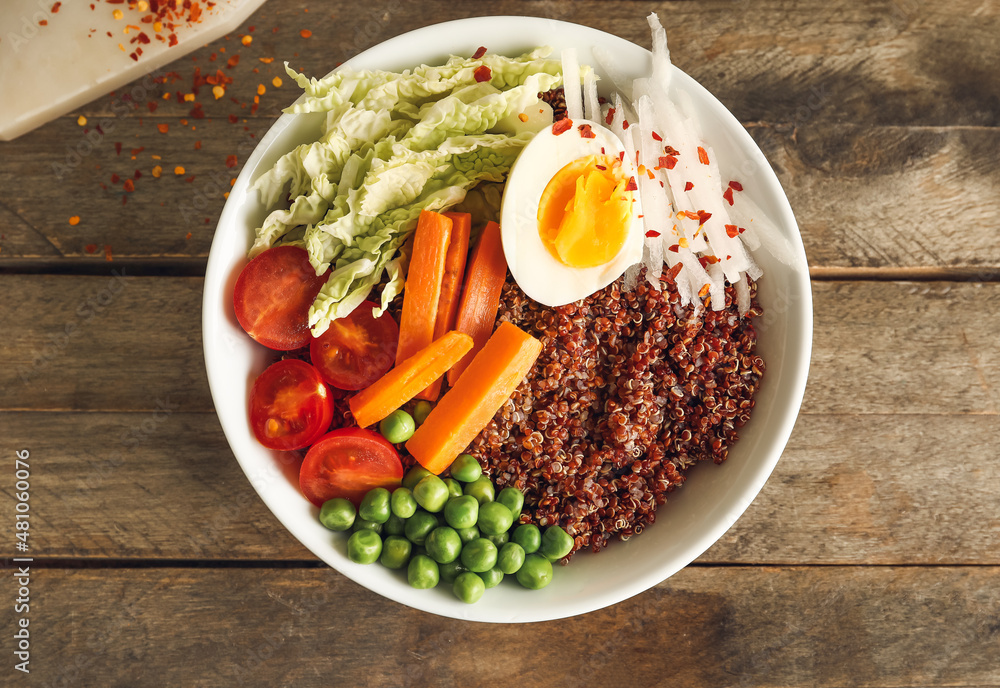 Healthy quinoa bowl with egg on wooden table