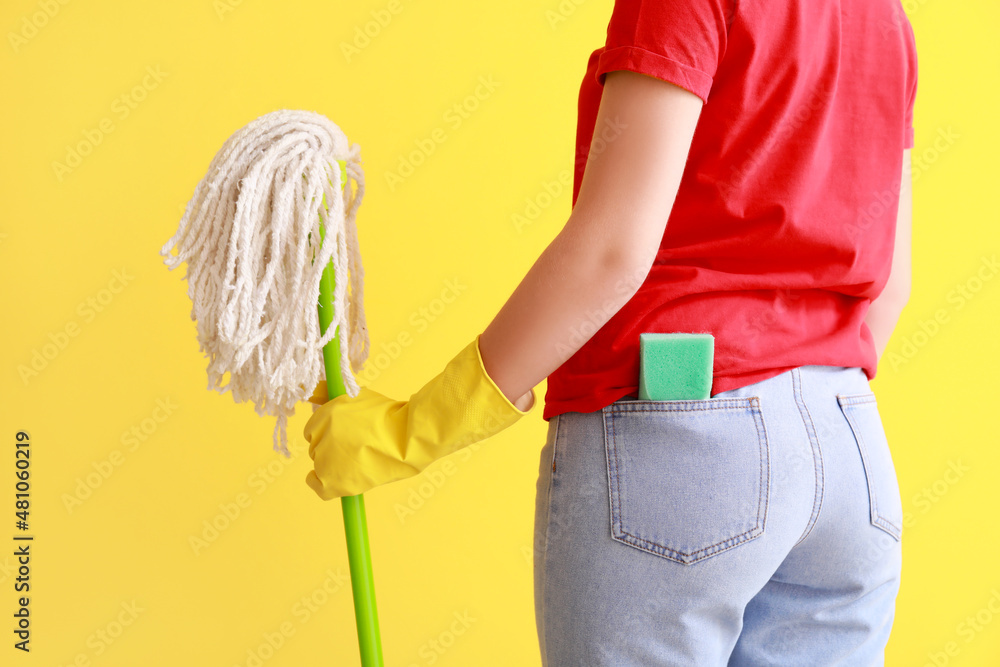 Young woman with sponge and floor mop on color background