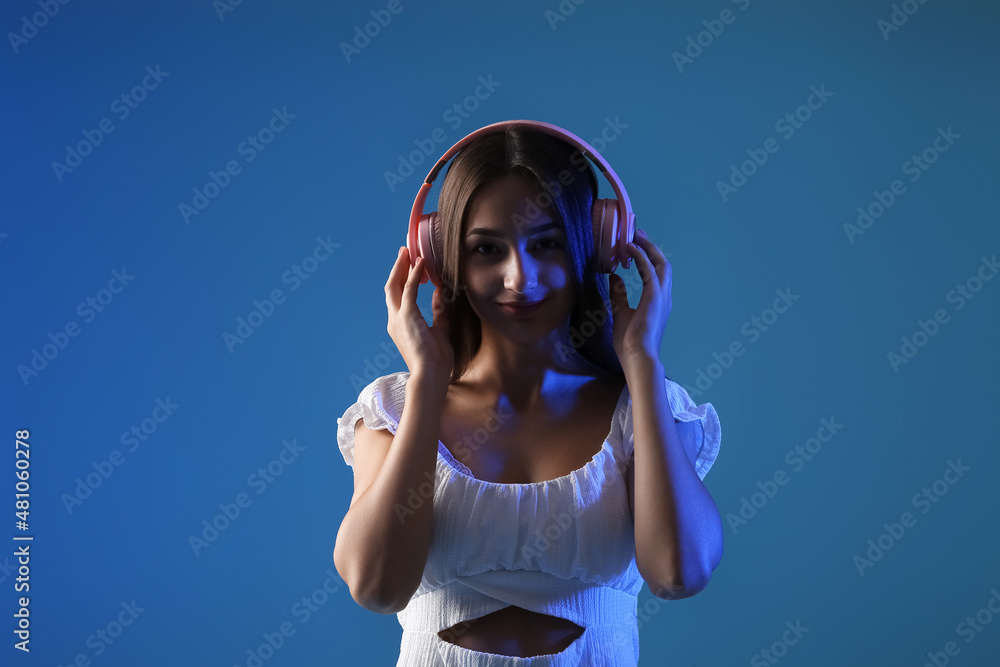 Cool young woman listening to music on color background