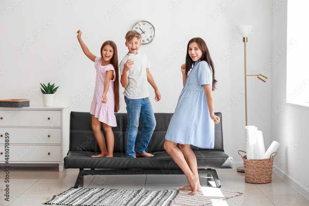 Happy woman and her children dancing at home