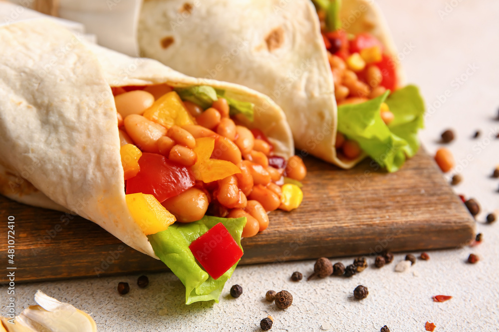 Board with delicious burritos and spices on light background, closeup