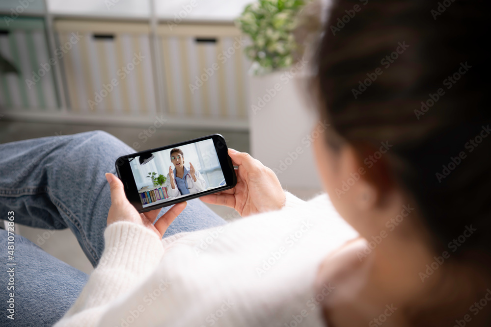 Young Asian woman sit on couch at home have video call with doctor use wireless internet connection 