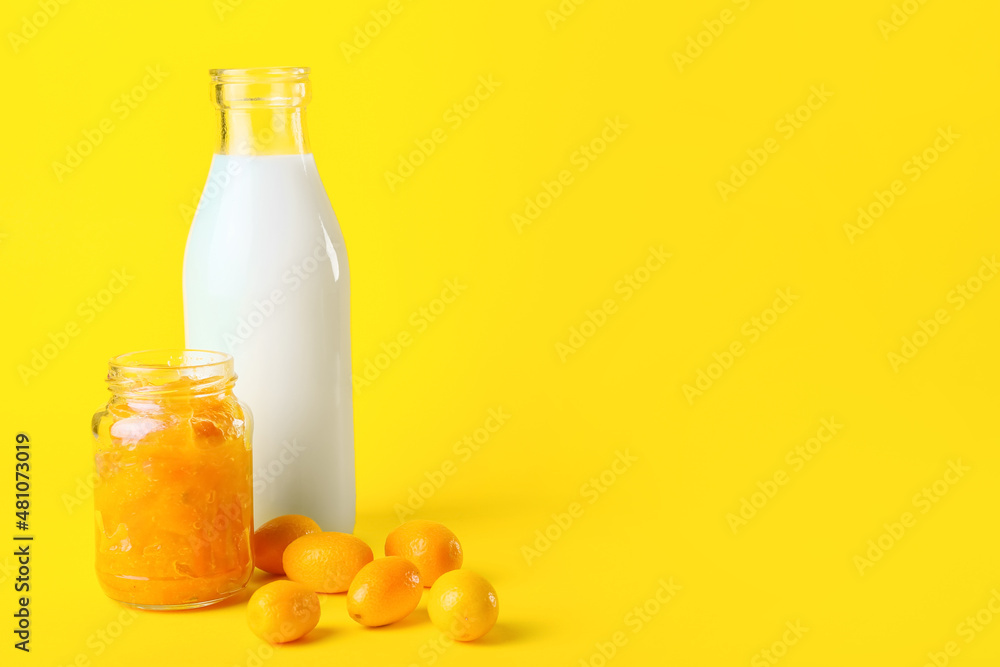 Jar of tasty kumquat jam and bottle with milk on yellow background