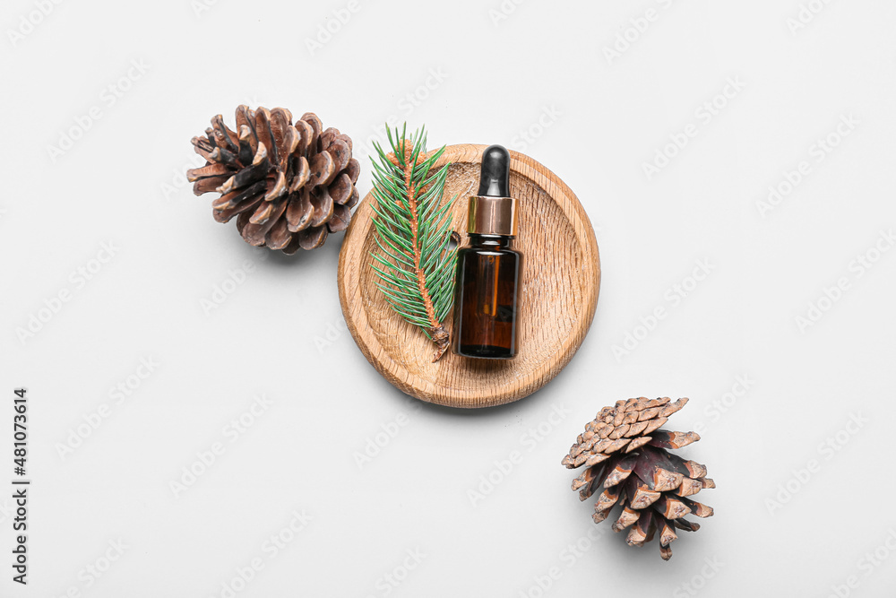 Composition with bottle of essential oil and pine cones on white background