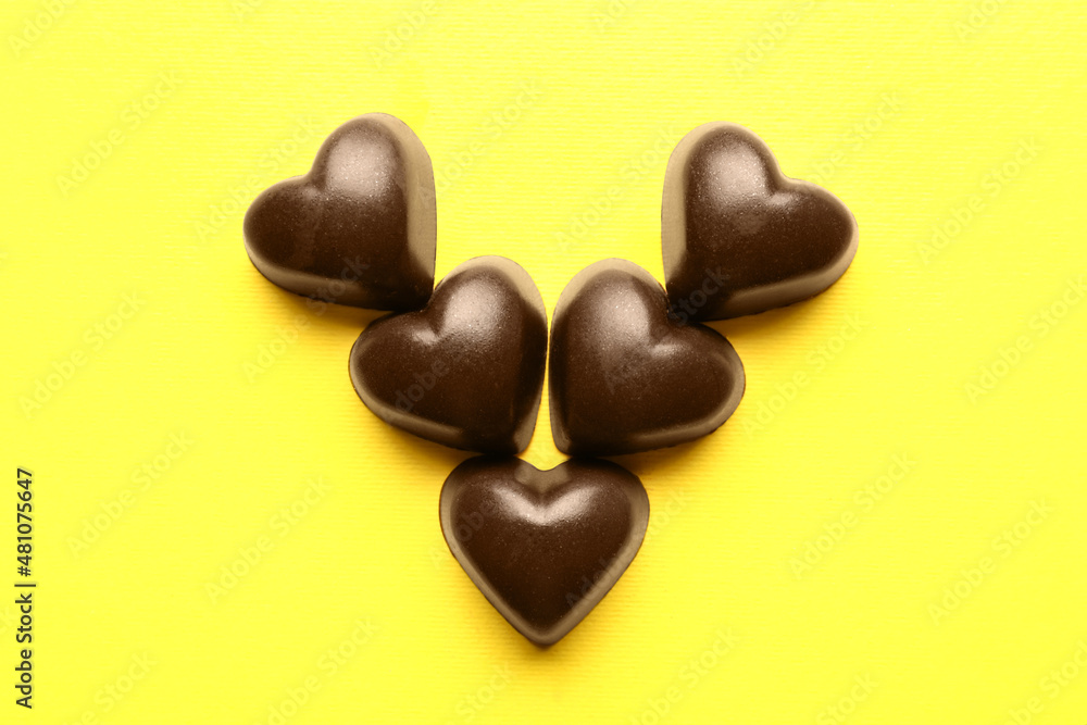 Tasty heart-shaped candies on yellow background