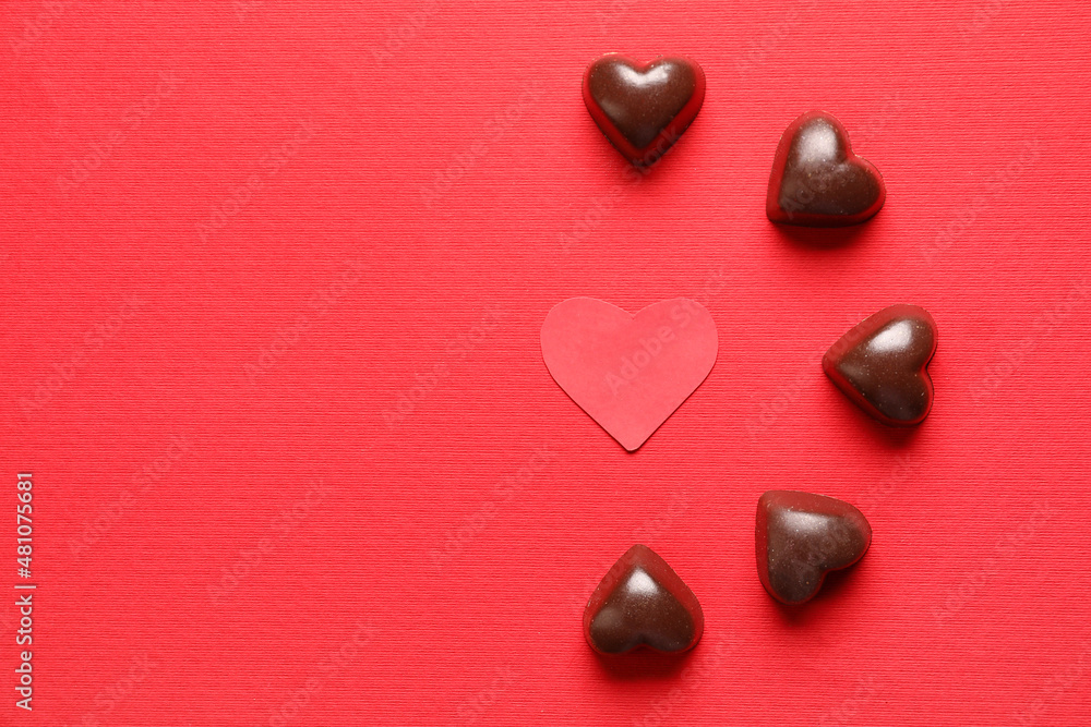 Tasty heart-shaped candies on red background